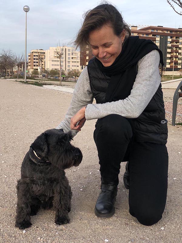 perro terrier negro sentado junto a su dueña Terrier negro sentado junto a chica que le acaricia