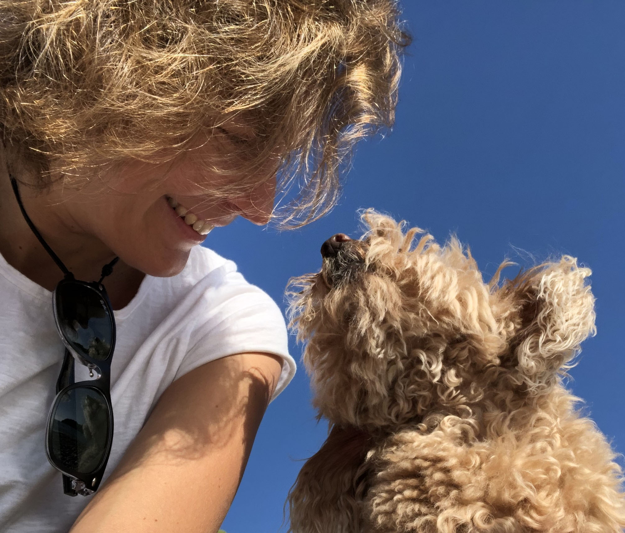 Chica rubia mirando a su perro caniche enano